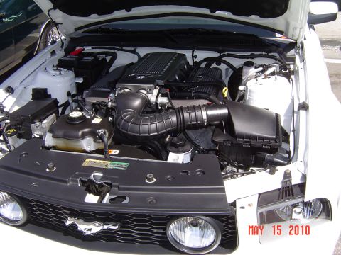 2005 Chevrolet Silverado 1500 - The engine bay of a white Ford Mustang is shown with the hood up, revealing the motor and front end details.