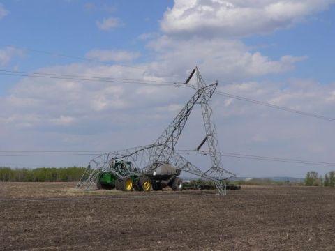 1994 Ford Bronco - A green John Deere tractor pulling an air seeder cart and wide seeding implement sits in a tilled field directly beneath a collapsed steel…