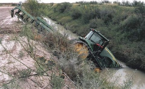 1994 Ford Bronco - A tractor is stuck in a muddy ditch, partially submerged in water.