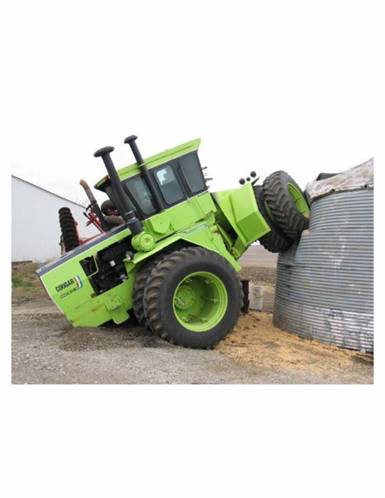 1994 Ford Bronco - A green tractor appears to be stuck, with its rear wheel wedged against the side of a large grain bin.