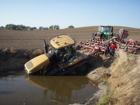 1994 Ford Bronco - Two tractors are stuck in the mud near a field. One is partially submerged in water.