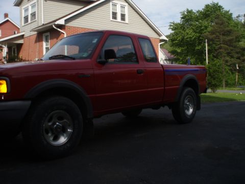1997 Ford Ranger - A red Ford Ranger pickup truck is parked in front of a house on a cloudy day.