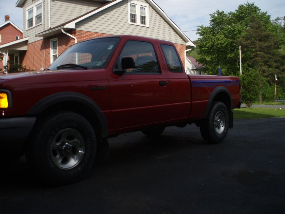 Red Ford Ranger pickup truck parked in driveway. Side view