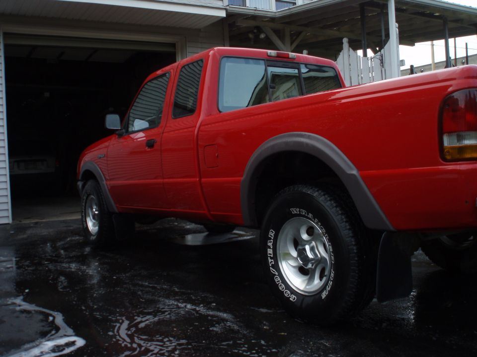 red pickup truck parked in driveway, wet ground