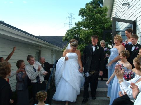 1993 Ford Taurus - A wedding party exits a building, with the bride and groom leading the way as guests celebrate.