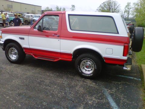1995 Ford Bronco - Side view of a two-tone red and white 1995 Ford Bronco parked outdoors.