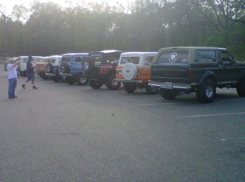 1995 Ford Bronco - Several Ford Broncos are parked in a lot, with a 1995 model visible from the rear.