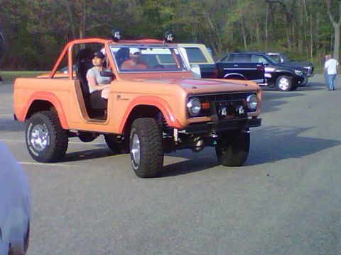 1995 Ford Bronco - Orange Ford Bronco parked outdoors with other vehicles visible in the background.