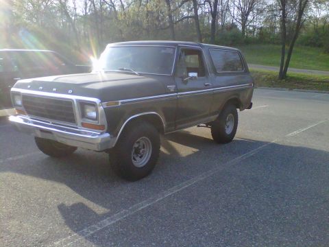 1995 Ford Bronco - This 1978 Ford Bronco is parked outdoors in a paved area with trees in the background.