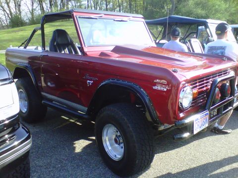 1995 Ford Bronco - This red convertible SUV features a hood scoop and a custom front bumper. The license plate is visible and reads CRUISIN.