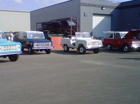 1995 Ford Bronco - A collection of Ford Broncos, including a rare convertible model, are parked together in a lot.