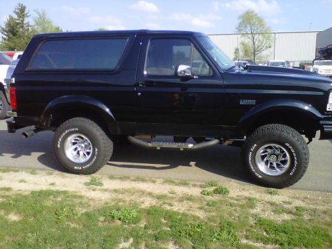 1995 Ford Bronco - Side profile of a black Ford Bronco SUV with aftermarket wheels and tires.