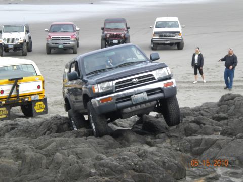1994 Ford Explorer - Multiple off-road vehicles gathered on a beach, with one Toyota 4Runner prominently featured on rocks.