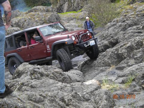 1994 Ford Explorer - A red Jeep Wrangler is shown off-roading on a rocky terrain, with a date stamp of 05.15.2010 in the corner.