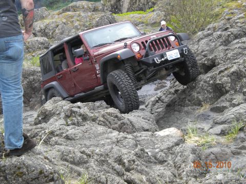 1994 Ford Explorer - A red Jeep Wrangler tackles a challenging rocky trail, demonstrating its off-road capabilities.