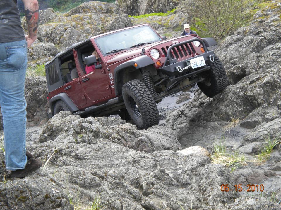 Red Jeep Wrangler navigating rocky terrain