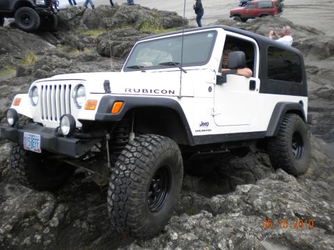 1994 Ford Explorer - White Jeep Wrangler Rubicon navigating a rocky trail, with other vehicles visible in the background.