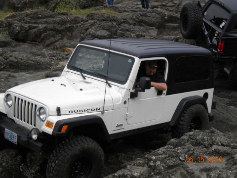 1994 Ford Explorer - A white Jeep Wrangler Rubicon navigates a rocky terrain, with another Jeep visible in the background.