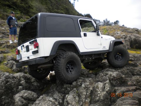 1994 Ford Explorer - A white Jeep Wrangler navigates a rocky landscape on a cloudy day.