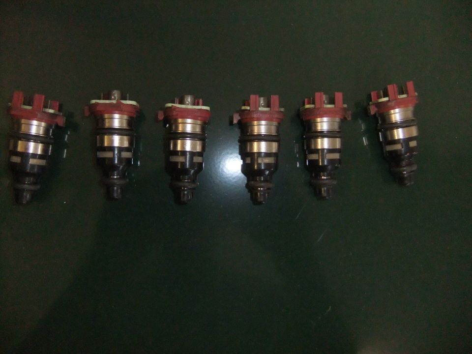 Six fuel injectors with red tops and black bodies