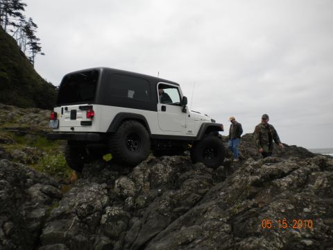 1994 Ford Explorer - A white Jeep Wrangler navigates a rocky coastal landscape with two companions observing.