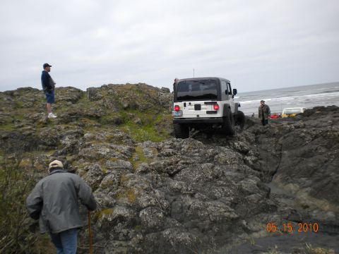1994 Ford Explorer - A group of people and vehicles navigate a rocky coastal area on a cloudy day.