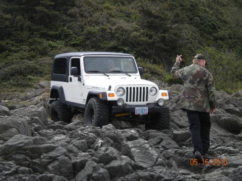 1994 Ford Explorer - A white Jeep Wrangler Rubicon is parked on a rocky shore with a person in a camouflage jacket standing nearby.