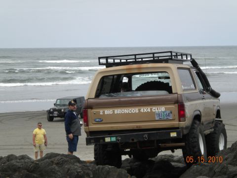 1994 Ford Explorer - Two men stand near a lifted Ford Bronco on a rocky beach, with another Jeep in the background.