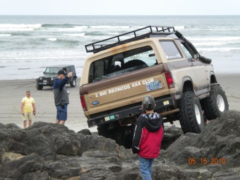 1994 Ford Explorer - A modified Ford Bronco 4x4 navigates rocks on a beach, with another Jeep and spectators nearby.