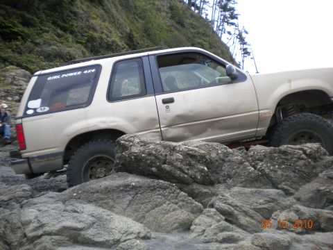 1994 Ford Explorer - A tan 1995 Ford Explorer navigates a rocky terrain near the coast.