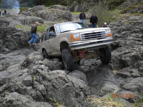 1994 Ford Explorer - A 1994 Ford Explorer tackles a challenging rocky path with a person walking nearby.