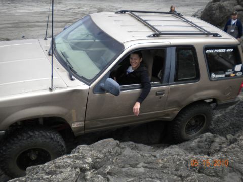 1994 Ford Explorer - A woman smiles from the driver's seat of a gold Ford Explorer navigating rocky terrain.