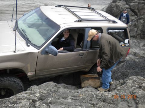 1994 Ford Explorer - A gold 1994 Ford Explorer is stuck on a rocky terrain, with people attending to it.