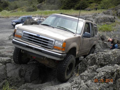 1994 Ford Explorer - A 1994 Ford Explorer is shown off-roading on a rocky coast, with another vehicle visible in the distance.