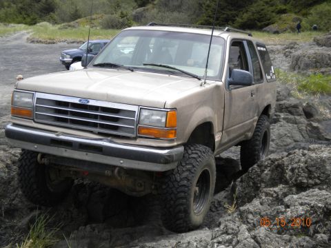 1994 Ford Explorer - A tan Ford Explorer navigates a rocky terrain, with another vehicle visible in the background.