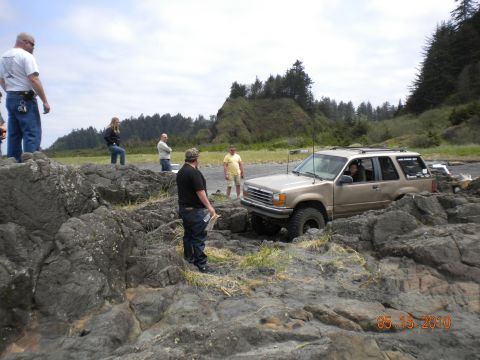 1994 Ford Explorer - 1994 Ford Explorer off-roading on a rocky coastal area with onlookers present.