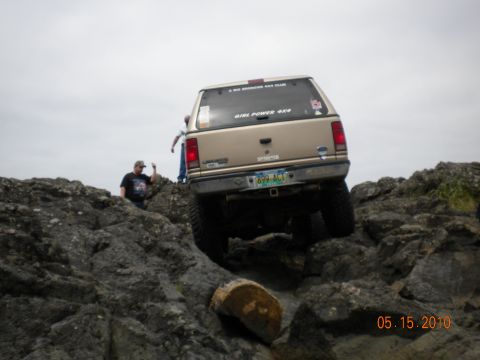 1994 Ford Explorer - A gold Ford Ranger is navigating a rocky terrain near the coast, with two people observing.