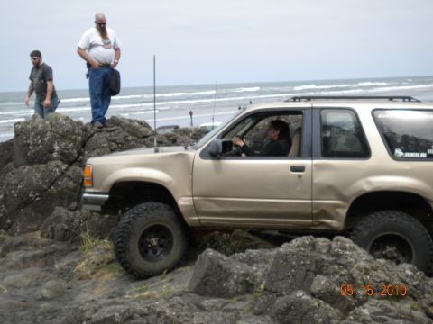 1994 Ford Explorer - A gold 1994 Ford Explorer navigates rocky terrain near the ocean shore.
