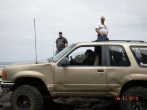 1994 Ford Explorer - A gold 1994 Ford Explorer is seen on a rocky shore with people around it.