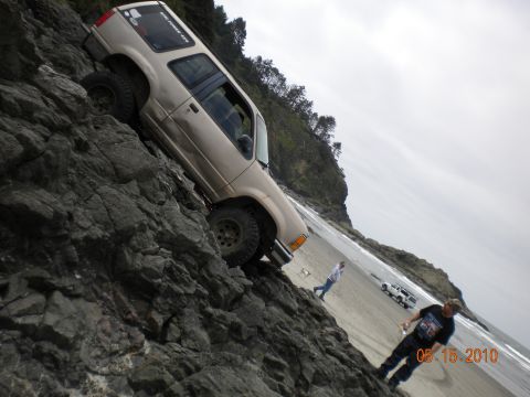 1994 Ford Explorer - A 1994 Ford Explorer navigates a rocky incline on the beach, with other vehicles and people present.