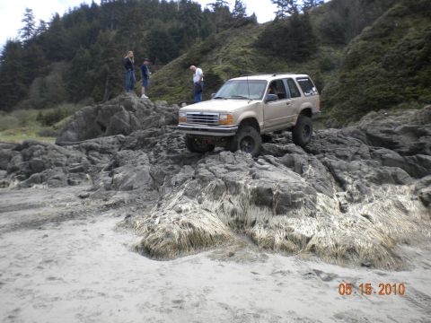 1994 Ford Explorer - A tan 1994 Ford Explorer navigates a rocky coastal terrain.