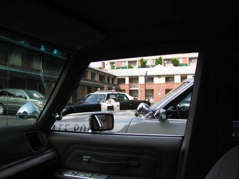 1991 Ford Crown Victoria - View from inside a vehicle shows two police cars parked in front of a motel building.