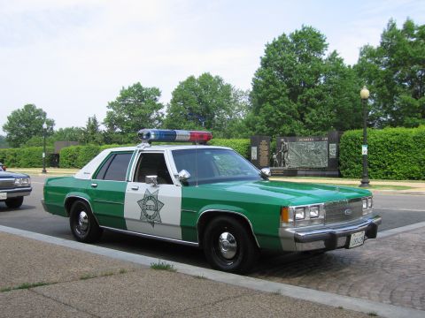 1991 Ford Crown Victoria - This sheriff's car features a light bar and the word "SHERIFF" on its door.