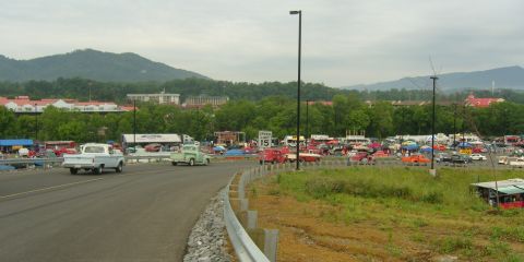 2007 Ford Mustang - A gathering of classic trucks and cars is visible in a large parking area, with a mountainous landscape behind the scene.