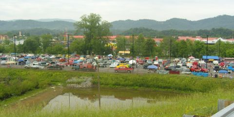 2007 Ford Mustang - A large gathering of vehicles parked in an outdoor lot, with tents and buildings visible behind them.