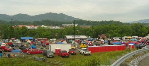 2007 Ford Mustang - A large outdoor gathering of vehicles, possibly a car show, with tents and portable restrooms visible.