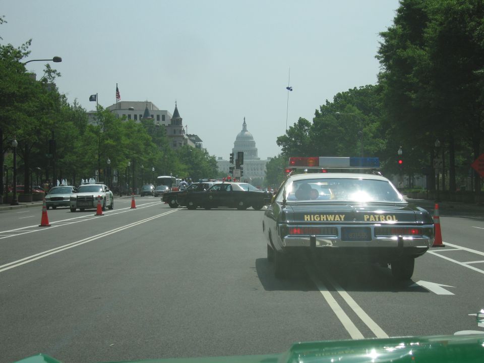 Dark Highway Patrol sedan with sun glare facing the US Capitol