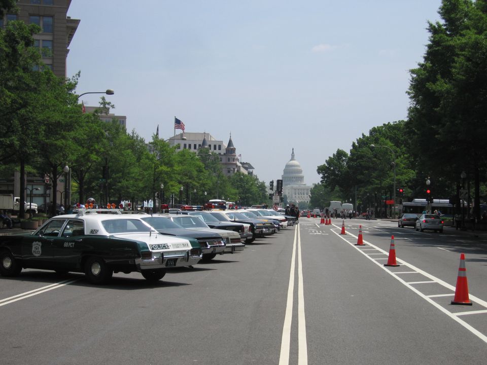 Long row of vintage police cars parked along a DC avenue toward the Capitol