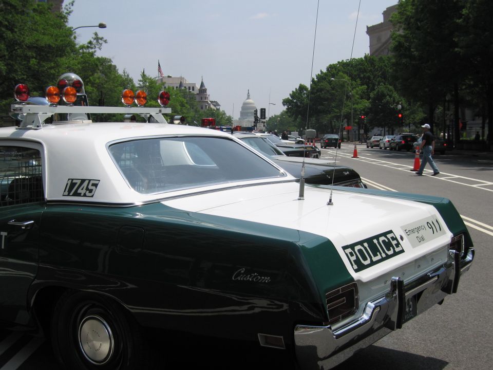 Rear roof of a green and white 1745 police sedan with the Capitol behind