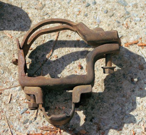 1976 Ford Ranchero - A single, heavily rusted suspension component rests on a textured concrete surface.